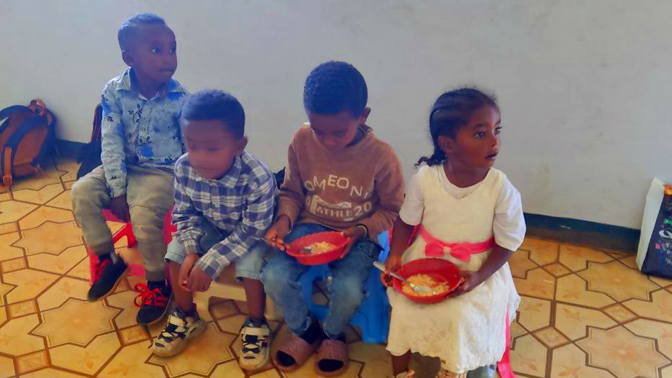 Bambini seduti con le ciotole del pranzo